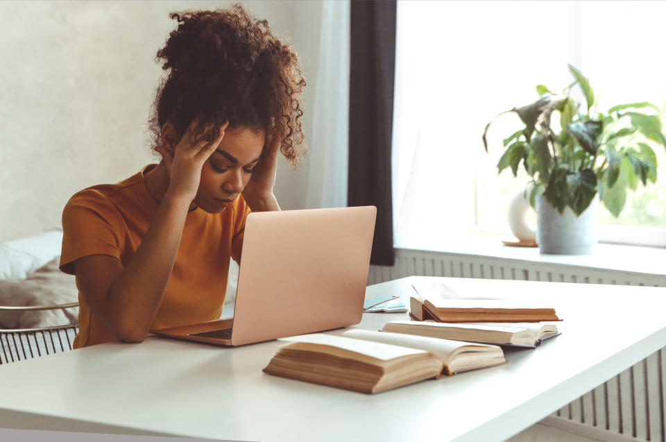 A young woman looks stressed out while working on her laptop