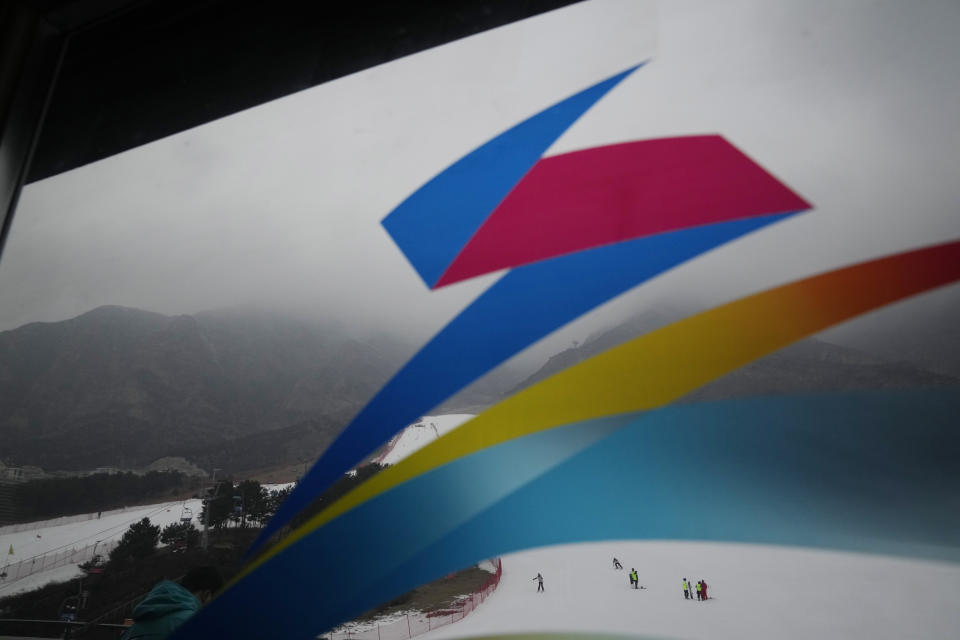 Visitors take to the slopes of the Vanke Shijinglong Ski Resort near the logo for the Beijing Winter Olympics in Yanqing on the outskirts of Beijing, China, Thursday, Dec. 23, 2021. The Beijing Winter Olympics is tapping into and encouraging growing interest among Chinese in skiing, skating, hockey and other previously unfamiliar winter sports. It's also creating new business opportunities (AP Photo/Ng Han Guan)