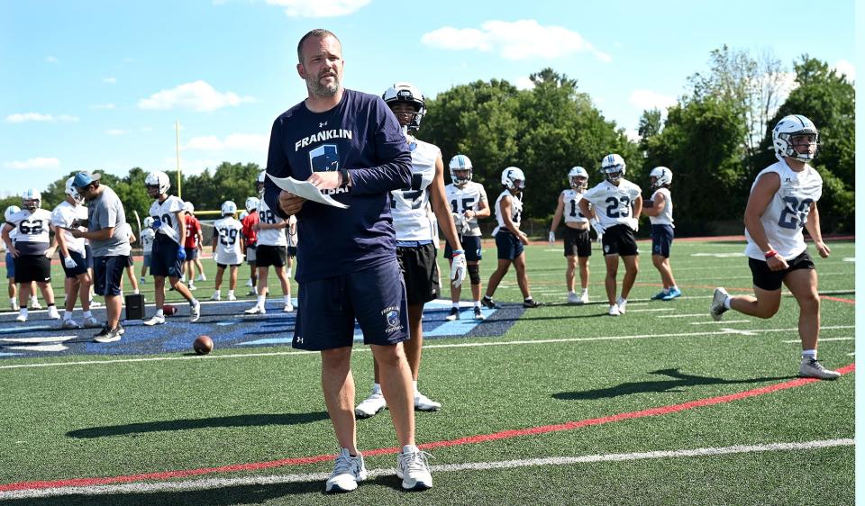 Franklin football coach Eian Bain watches his players as practice gets underway, Aug. 19, 2022.