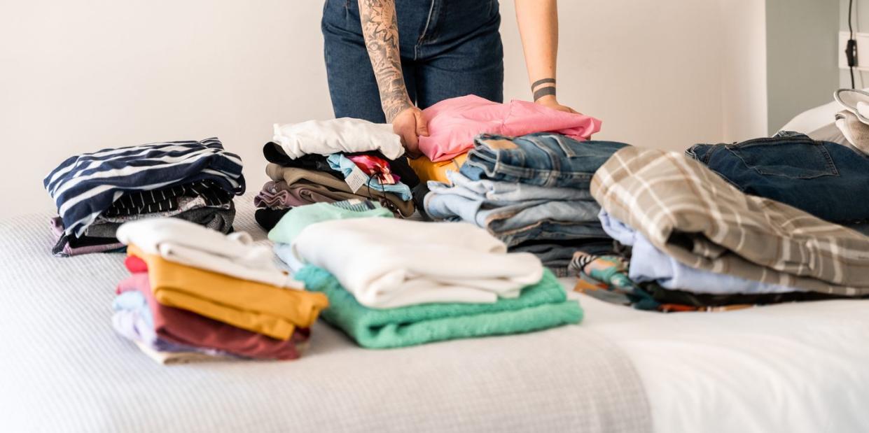 swedish death cleaning unrecognizable woman folding the clothes from her closet on the bed