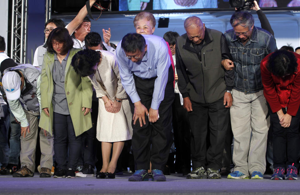 Taipei city mayor and city mayoral candidate Ko Wen-je, center, Ko's families, team members bow to supporters for winning in Taipei, Taiwan, Sunday early morning, Nov. 25, 2018. Taiwan's ruling party suffered a major defeat Saturday in local elections seen as a referendum on the administration of the island's independence-leaning president amid growing economic and political pressure from China. (AP Photo/Chiang Ying-ying)