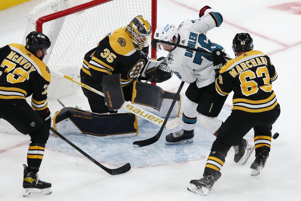 San Jose Sharks' Jonathan Dahlen (76) and Boston Bruins' Brad Marchand (63) battle for control of the puck in front of Bruins goaltender Linus Ullmark (35) during the third period of an NHL hockey game, Sunday, Oct. 24, 2021, in Boston. (AP Photo/Michael Dwyer)