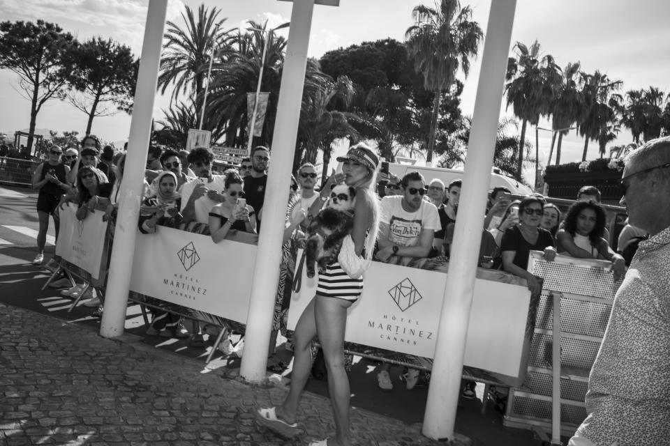 A woman with her dog leaves the Martinez hotel during the 75th international film festival, Cannes, southern France, Tuesday, May 24, 2022. (AP Photo/Petros Giannakouris)