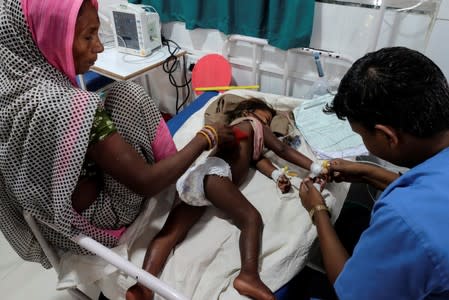 Child suffering from acute encephalitis syndrome is treated by a doctor at a hospital in Muzaffarpur