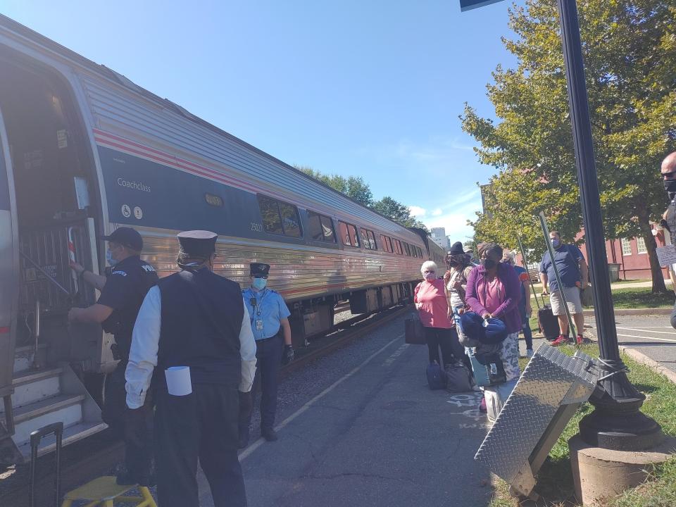 people boarding the amtrak train stopped at a small station