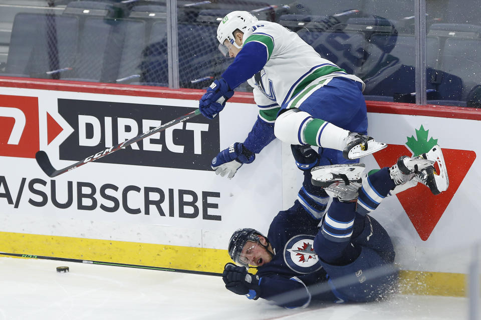 Vancouver Canucks' Alex Chiasson (39) jumps over Winnipeg Jets' Nate Schmidt (88) during first-period NHL hockey game action in Winnipeg, Manitoba, Thursday, Jan. 27, 2022. (John Woods/The Canadian Press via AP)