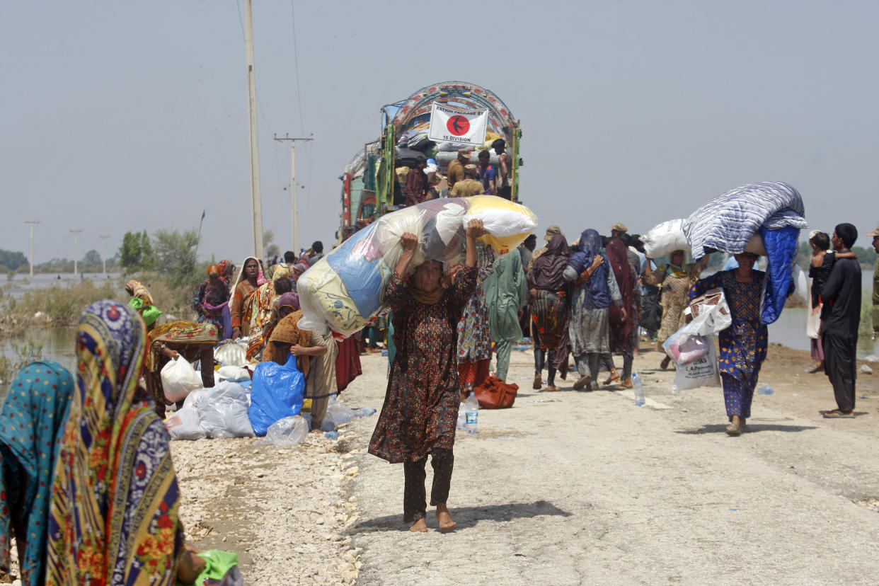 Victims of heavy flooding from monsoon rains receive relief aid from the Pakistani Army in the Qambar Shahdadkot district of Sindh Province, Pakistan, Friday, Sept. 9, 2022. U.N. Secretary-General Antonio Guterres appealed to the world for help for cash-strapped Pakistan after arriving in the country Friday to see the climate-induced devastation from months of deadly record floods. (AP Photo/Fareed Khan)