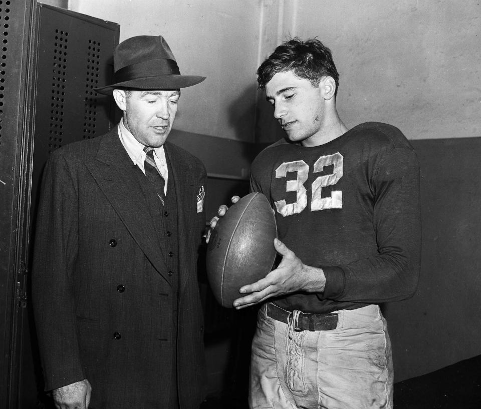 FILE - Notre Dame football coach Frank Leahy, left, and Johnny Lujack, right, are shown in the locker room after the Fighting Irish's 20-0 victory over Army in New York, Nov. 6, 1943. Lujack, the Heisman Trophy winner who led Notre Dame to three national championships in the 1940s, died in Florida on Tuesday, July 25, 2023, following a brief illness. He was 98.(AP Photo/Harry Harris)