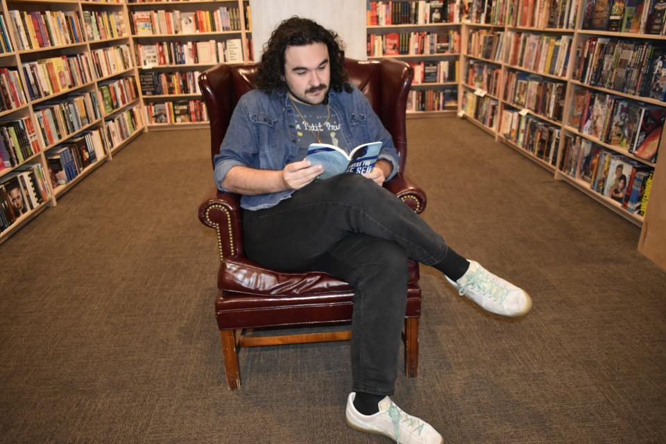 Matthew Woods, events coordinator at Morgenstern Books, sits in one of the four leather upholstered wingback chairs placed in the store for comfortable reading.