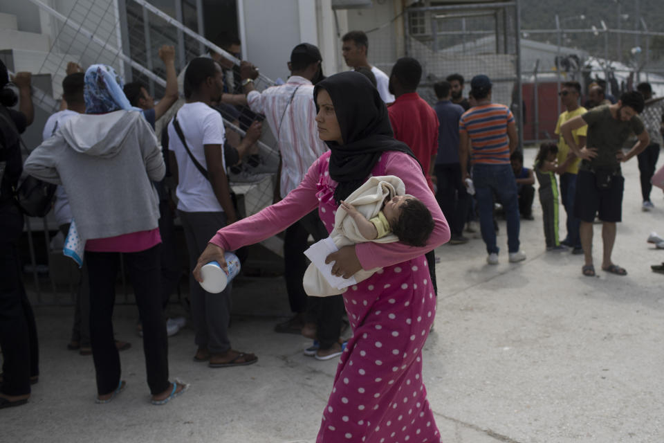 FILE - In this Friday, May 4, 2018 file photo, a woman walks with her baby as migrants and refugees wait outside the UNHCR offices for their papers inside the camp of Moria, Lesbos island, Greece. European governments breathed a sigh of relief as the European Union reached a deal with Turkey designed to stop hundreds of thousands of refugees and migrants heading into the heart of Europe. For many of those who had fled war, hunger and poverty hoping for a bright future on the continent, the deal shattered their dreams. (AP Photo/Petros Giannakouris, File)