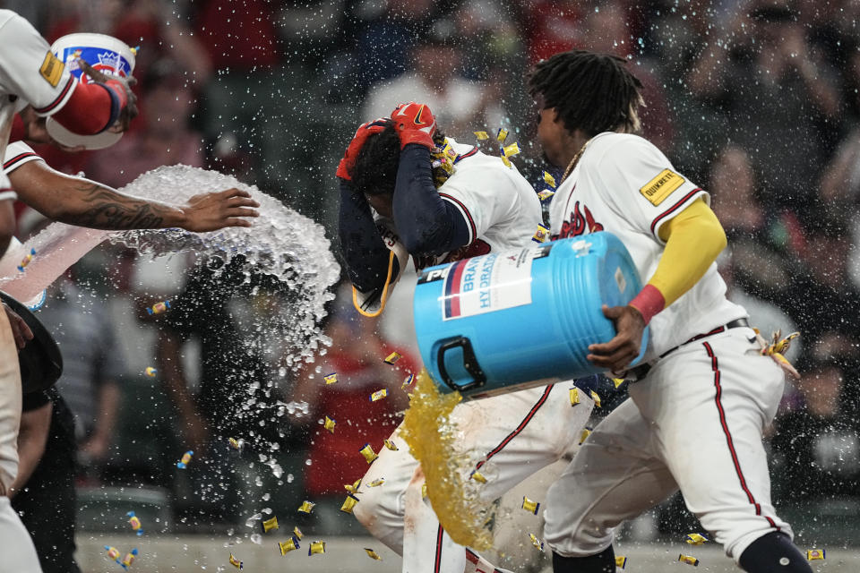 CORRECTS TO THREE-RIN HOME RUN NOT TWO-RUN HOME RUN - Atlanta Braves' Ozzie Albies, second from right, is doused by teammate Ronald Acuna Jr. after hitting a winning three-run home run in the 10th inning of a baseball game against the New York Mets, Thursday, June 8, 2023, in Atlanta. (AP Photo/John Bazemore)