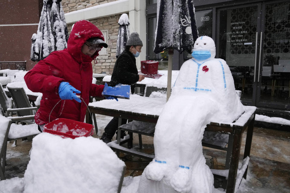 Workers at a restaurant build a snowman in the shape of a pandemic first responder with a protective suit and a mask in Beijing, China, Sunday, Nov. 7, 2021. An early-season snowstorm has blanketed much of northern China including the capital Beijing, prompting road closures and flight cancellations. (AP Photo/Ng Han Guan)