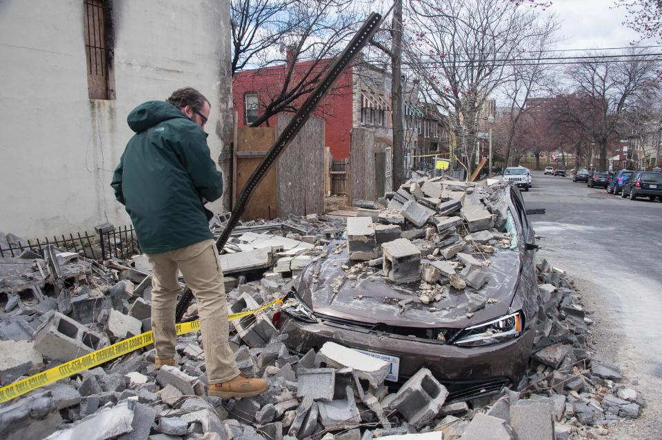 <p>An insurance company employee checks the damage to a car after a partially burnt building collapsed due to strong winds in Northeast Washington on March 2, 2018. (Photo: Nicholas Kamm/AFP/Getty Images) </p>