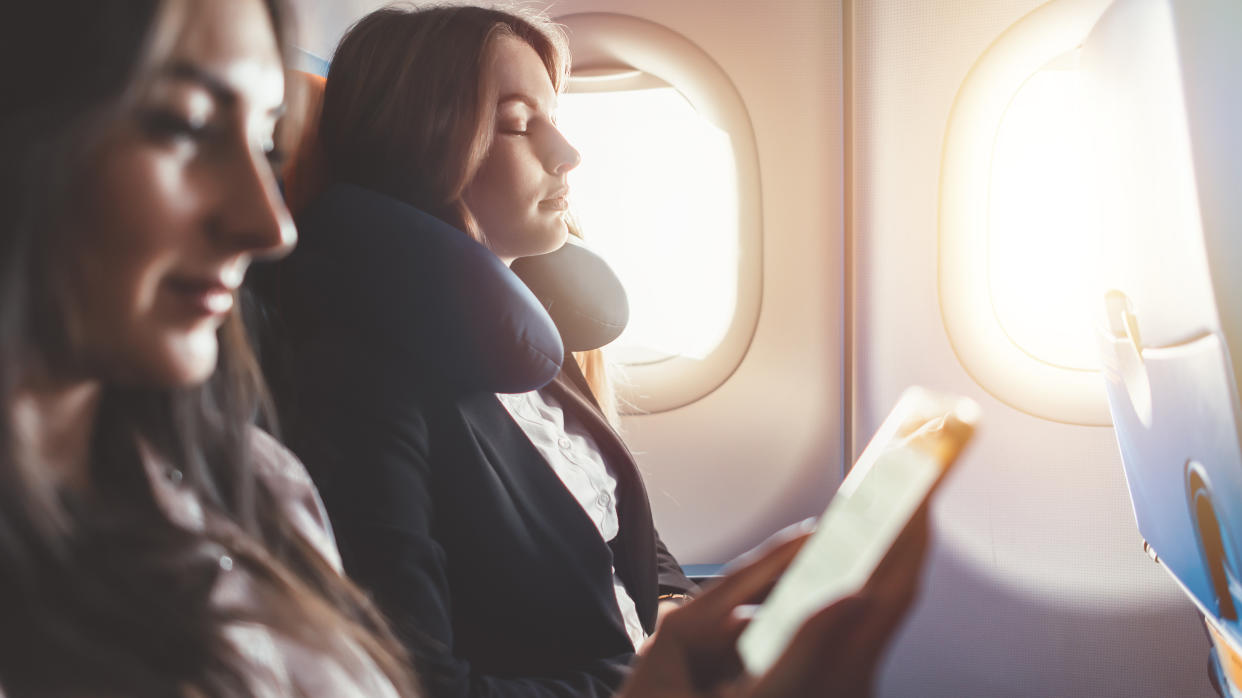 Two females going on business trip by plane. A woman reading an e-book on a smartphone - Credit: undrey - stock.adobe.com