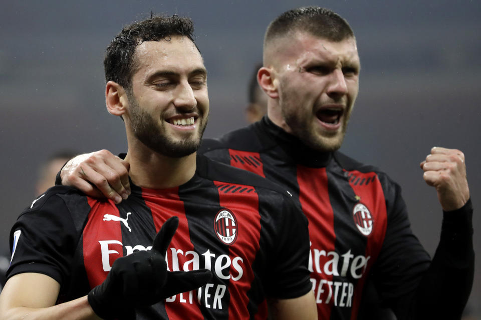 Hakan Chalhanoglu (izquierda), del Milan, festeja con su compañero Ante Rebic, tras anotar ante la Lazio en un encuentro del miércoles 23 de diciembre de 2020 (AP Foto/Luca Bruno)