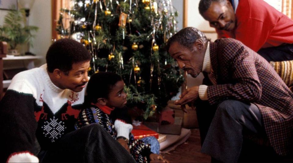 Sammy David Jr. looking at a child by a christmas tree