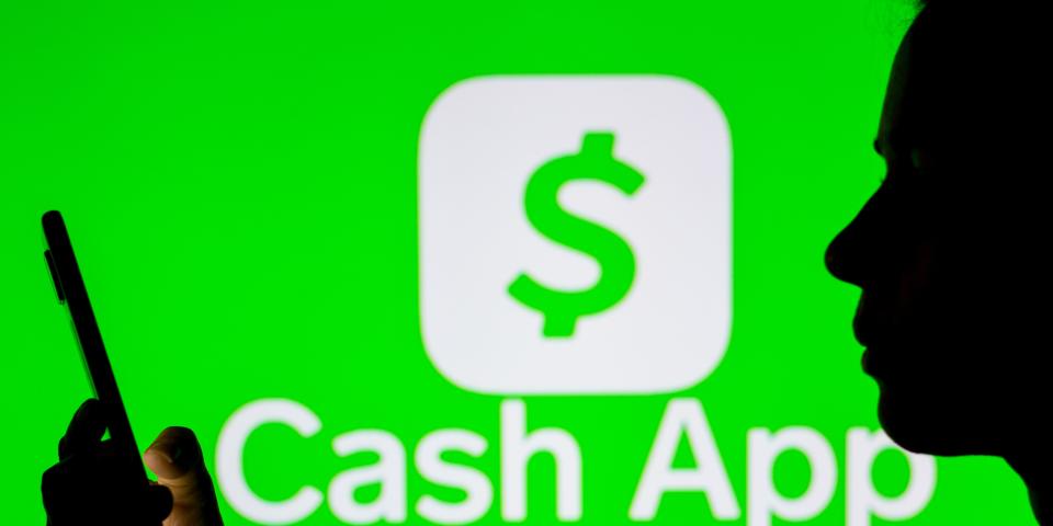 cash app logo behind person on phone in silhouette