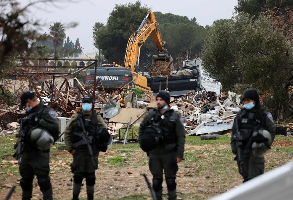 Israeli forces stand guard as machinery clean the ruins of the Palestinian Salhiya family’s house, in the Sheikh Jarrah neighbourhood (AFP via Getty Images)