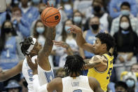 Michigan guard Eli Brooks (55) passes while North Carolina forward Armando Bacot (5) and guard Caleb Love defend during the first half of an NCAA college basketball game in Chapel Hill, N.C., Wednesday, Dec. 1, 2021. (AP Photo/Gerry Broome)