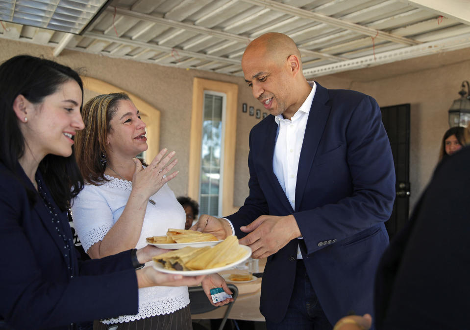 FILE - In this April 20, 2019 photo, Democratic presidential candidate Sen. Cory Booker eats a tamale while visiting a home in Las Vegas. Booker rose to fame as a New Jersey mayor and senator but his mom and other relatives have lived in Las Vegas for years. Now, he’s working those local connections to set himself apart from the crowded pack in a state that could be decisive. (AP Photo/John Locher, File)