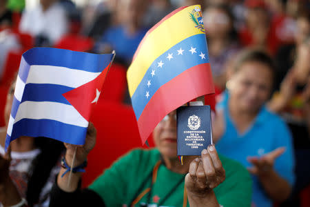 A supporter of Venezuela's President Nicolas Maduro holding a copy of the Venezuelan constitution and flags of Venezuela and Cuba, takes part in a gathering in support of his government outside the Miraflores Palace in Caracas, Venezuela January 26, 2019. REUTERS/Carlos Garcia Rawlins/Files