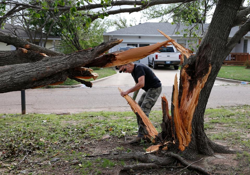 John Walls cleans up damaged trees, Thursday, April, 20, 2023, in Shawnee, Okla., after tornado moved through the area Wednesday night in Shawnee, Okla.