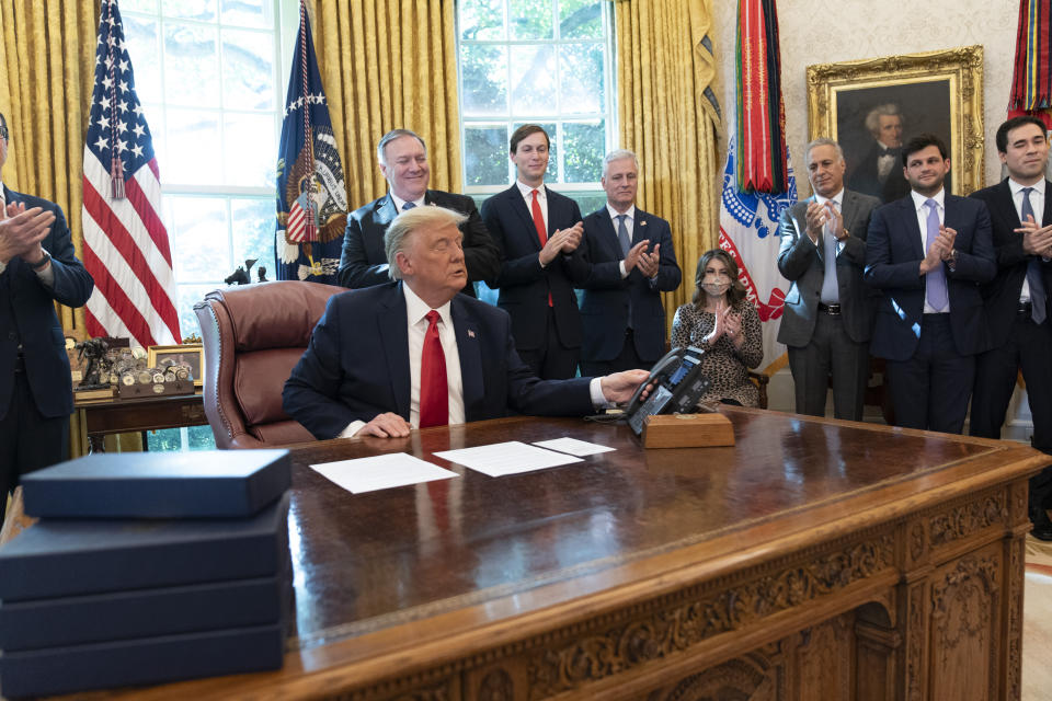 President Donald Trump hangs up a phone call with the leaders of Sudan and Israel, as Treasury Secretary Steven Mnuchin, left, Secretary of State Mike Pompeo, White House senior adviser Jared Kushner, National Security Adviser Robert O'Brien, and others applaud in the Oval Office of the White House, Friday, Oct. 23, 2020, in Washington. (AP Photo/Alex Brandon)