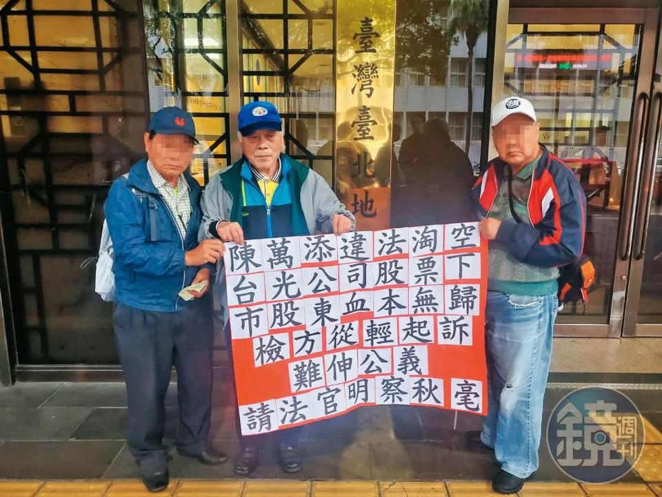 金山財神廟前董事長鄭楠興（中）與受害股東代表在法院外拉布條，籲請法官對陳萬添從重量刑。（讀者提供）