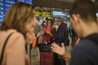 Passengers wait in the airport in Santa Cruz de Tenerife, Spain, Sunday, Feb. 23, 2020. Flights leaving Tenerife have been affected after storms of red sand from Africa's Saharan desert hit the Canary Islands. (AP Photo/Andres Gutierrez)