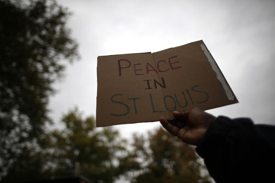 A man holds up a sign at a candlelight vigil in St. Louis, Missouri, October 9, 2014. A 32-year-old white St. Louis police officer fatally shot 18-year-old Vonderrit Myers Jr. after the officer, who was off duty working for a private security company, saw Myers and two friends running and pursued them, according to a statement issued by the St. Louis police department. (REUTERS/Jim Young)