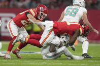 Miami Dolphins quarterback Tua Tagovailoa, bottom, is stopped by Kansas City Chiefs defensive end Mike Danna and linebacker Drue Tranquill, left, during the first half of an NFL football game Sunday, Nov. 5, 2023, in Frankfurt, Germany. (AP Photo/Michael Probst)