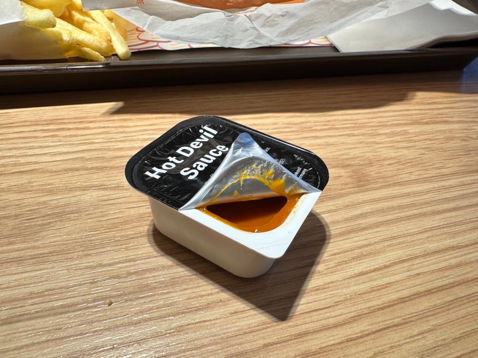 partially open mcdonalds hot devil sauce packet on a wood table