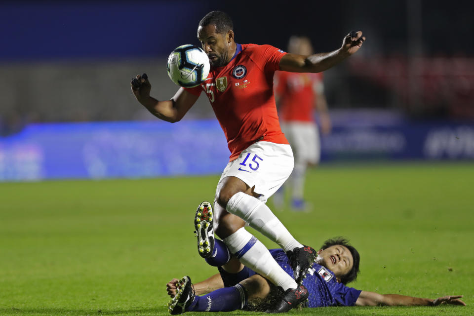 Japan's Ayase Ueda, bottom, and Chile's Jean Beausejour vie for the ball during a Copa America Group C soccer match at Morumbi stadium in Sao Paulo, Brazil, Monday, June 17, 2019. (AP Photo/Andre Penner)