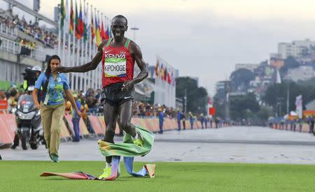 2016 Rio Olympics - Athletics - Final - Men's Marathon - Sambodromo - Rio de Janeiro, Brazil - 21/08/2016. First placed Eliud Kipchoge (KEN) of Kenya gets feet tangled up in finish line tape. REUTERS/Lucy Nicholson