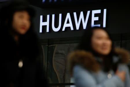 FILE PHOTO: A woman walks past a Huawei shop in Beijing, China, January 29, 2019. REUTERS/Thomas Peter/File Photo