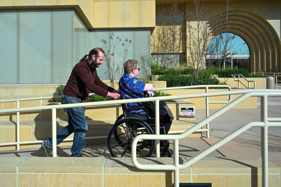 Ilya Edinburg helps his partner Evan Underwood return his computer to the California Department of General Services earlier this month after quitting his IT job because he was not allowed to work remotely full-time any longer. Underwood said navigating the ramps and juggling ice packs, a fan and other things required by his health condition was too difficult.