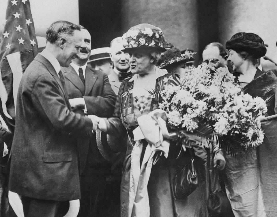 FILE - In this Aug. 27, 1920 file photo, New York Gov. Alfred E. Smith, welcomes Carrie Chapman Catt, women's suffrage leader, on her return from Tennessee, the last state to ratify the 19th Amendment giving women the right to vote, in New York. Catt carries a bouquet of blue and yellow flowers, colors of the National American Woman's Suffrage Association. (AP Photo)