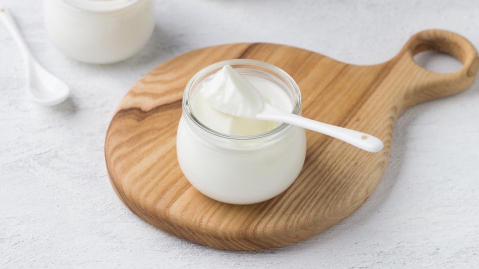 A cup of yogurt on a wooden tray, which can help with heartburn