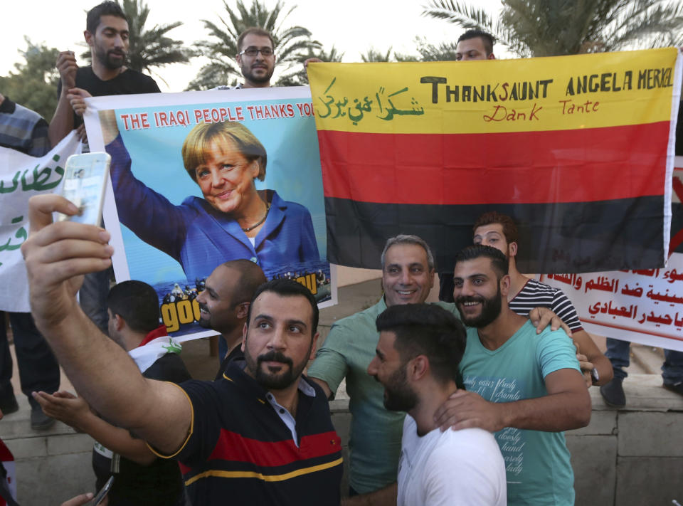 FILE - Iraqi protesters take a selfie with a poster of German Chancellor Angela Merkel and a German flag, during demonstrations against corruption in Tahrir Square in Baghdad, Iraq, Friday, Sept. 4, 2015. The U.N. refugee agency says it's giving its highest award to former German Chancellor Angela Merkel for her efforts to bring in more than 1 million refugees — mostly from Syria — into Germany, despite some pockets of criticism at both home and abroad. (AP Photo/Hadi Mizban, File)