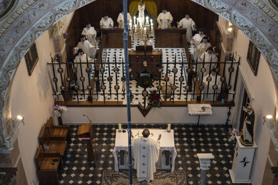 A priest celebrates Mass with cloistered nuns in the Catholic Monastery of St. Catherine on the Greek island of Santorini on Tuesday, June 14, 2022. The nuns' vocation is to pray tirelessly for the church and the world, symbolized by the globe next to the grille that separates the cloistered space from the outside world. (AP Photo/Petros Giannakouris)