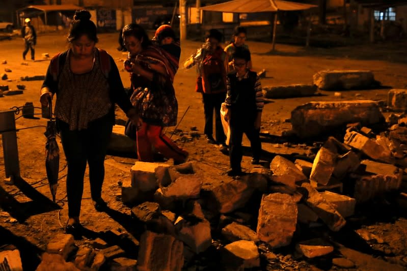 People walk through a barricade as coca farmers and supporters of Bolivia's ousted President Evo Morales stage a blockade of an entrance to Sacaba