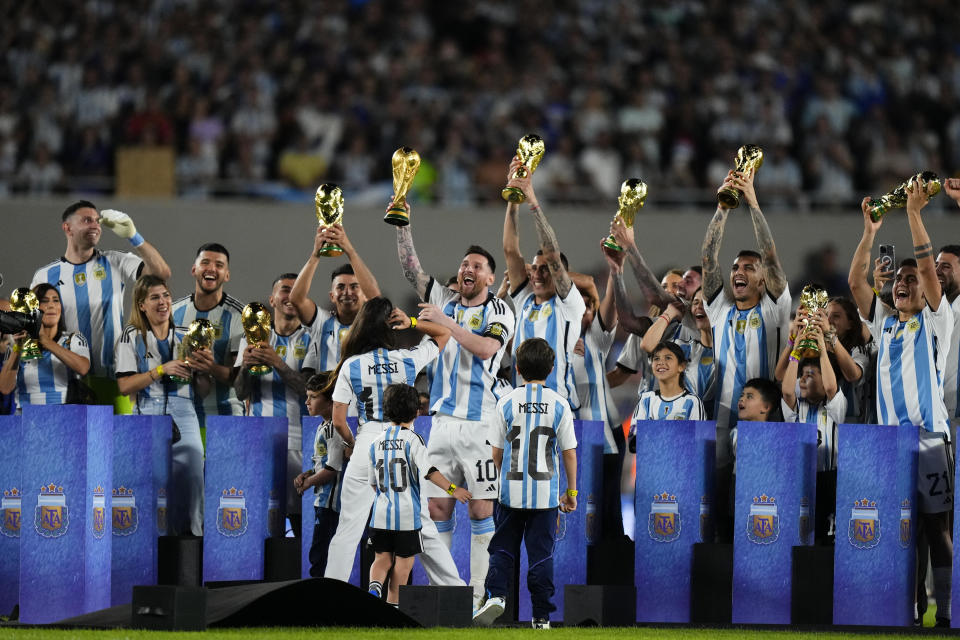 Argentina's Lionel Messi, center, raises the FIFA World Cup trophy during a celebration ceremony for local fans after an international friendly soccer match against Panama in Buenos Aires, Argentina, Thursday, March 23, 2023. (AP Photo/Natacha Pisarenko)