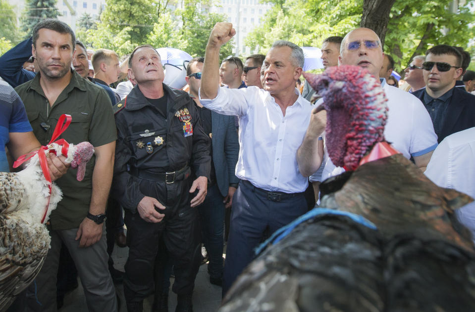 Vladimir Plahotniuc, the leader of the Moldova's Democratic party, and the country's de facto leader, clenches his fist gesturing next to interim president Pavel Filip, right, as people hold turkeys before throwing them over the fence of the Modovan presidency building in Chisinau, Moldova, Sunday, June 9, 2019. Moldova's interim president Pavel Filip has dissolved parliament and called for snap elections on Sept. 6 amid a months-long political crisis, announcing his decision shortly after his appointment on Sunday by the Constitutional Court to replace president Igor Dodon.(AP Photo/Roveliu Buga)