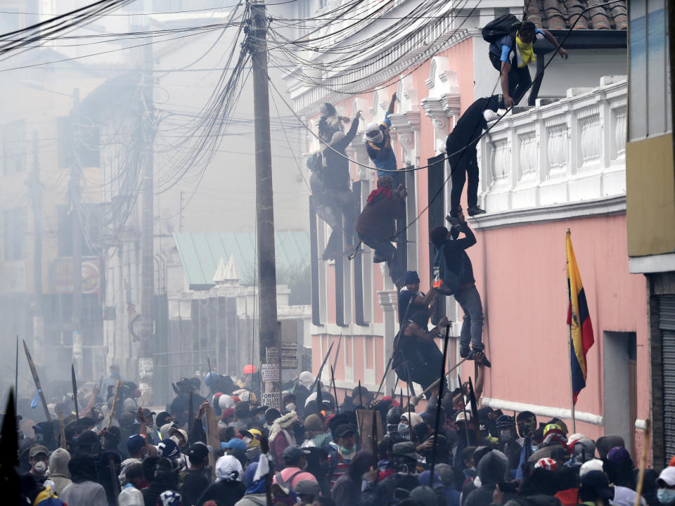 Anti-government demonstrators scale the facade of a residence to reach the rooftop, looking for a better vantage point to battle with police, in Quito, Ecuador, Friday, Oct. 11, 2019. Protests, which began when President Lenin Moreno's decision to cut subsidies led to a sharp increase in fuel prices, persisted for days. (AP Photo/Dolores Ochoa)