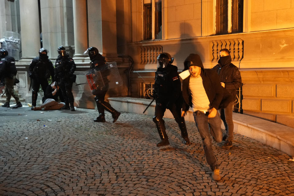 A protester runs away during clashes with anti-riot police in Belgrade, Serbia, Sunday, Dec. 24, 2023. Police in Serbia have fired tear gas to prevent hundreds of opposition supporters from entering the capital's city council building to protest what election observers said were widespread vote irregularities during a general election a week ago. (AP Photo/Darko Vojinovic)