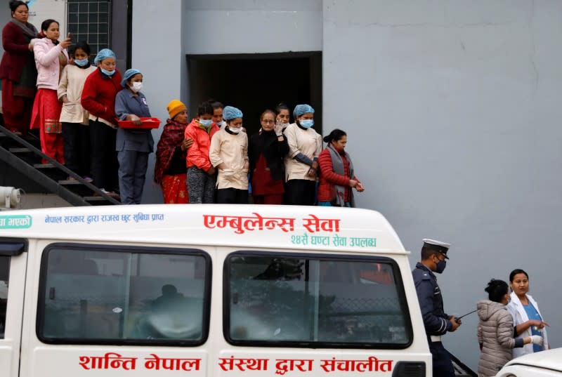 Hospital staff observe as the bodies of eight Indian tourists who died due to suspected suffocation are carried inside an ambulance while being taken for postmortem in Kathmandu