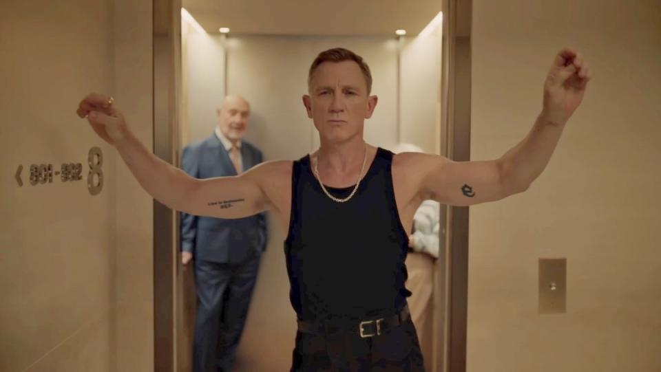 Daniel Craig in black slacks and a black tank top dancing in a hallway