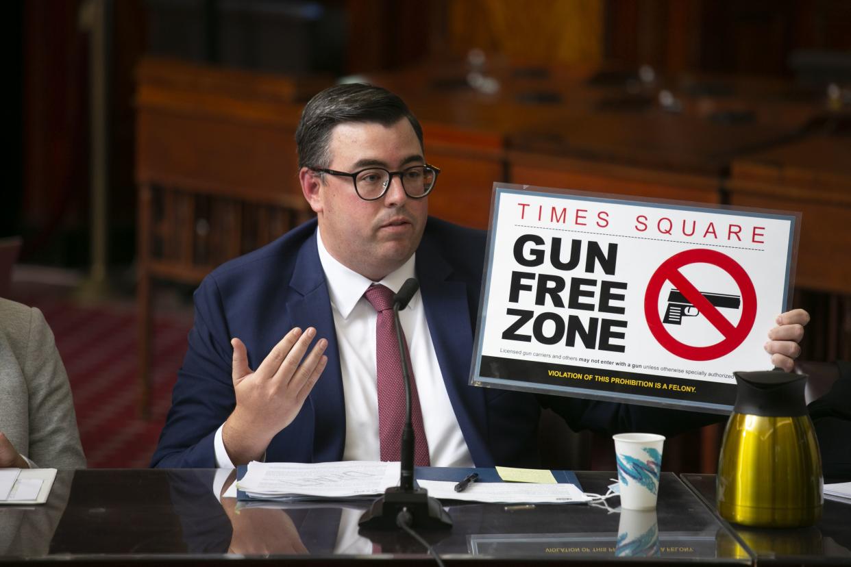 Robert Barrows of the New York City Police Department holds up a "gun free zone" sign during a City Council meeting Tuesday, Aug. 30, 2022.