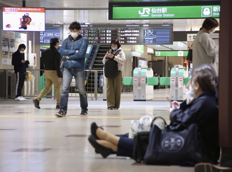 People sit on the floor at a station as train services are suspended following an earthquake in Sendai