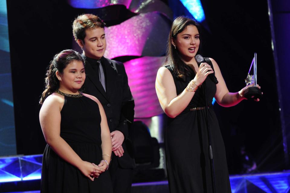 In behalf of their mother, (left to right) Gela, Arjo and Ria, Sylvia Sanchez's children receive the "Best Single Performance by an Actress" award during the 26th Star Awards for TV held at the Henry Lee Irwin Theater in Ateneo De Manila University on 18 November 2012. (Angela Galia/NPPA images)